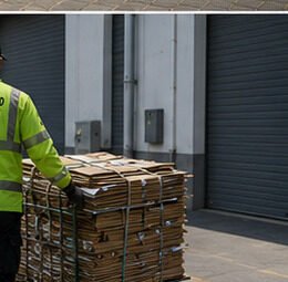 Staff member pushing a cart of bundled cardboard